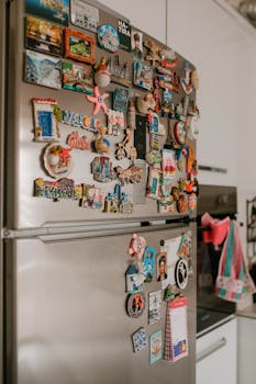 A collection of colorful souvenir magnets on a refrigerator in a modern kitchen.