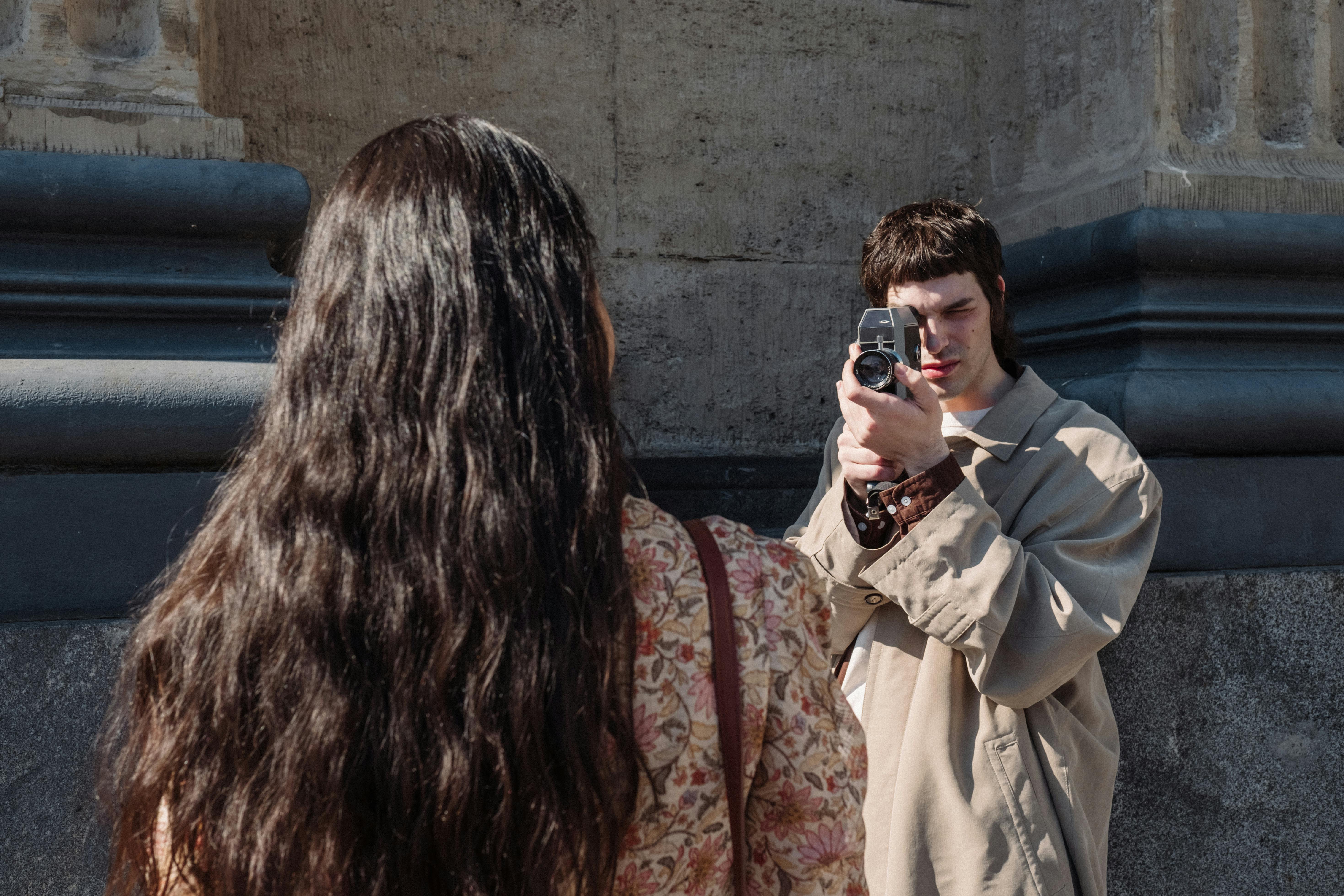A person captures a friend on film with a vintage camera during a casual outdoor photoshoot.
