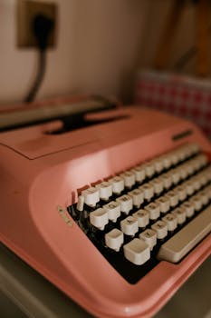 Classic pink typewriter on desk with retro vibes and warm lighting.