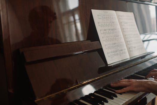 Close-up of hands playing piano with sheet music reflecting on the piano's surface.
