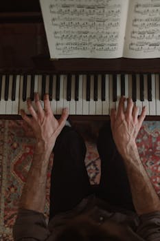 An overhead shot capturing a pianist's hands playing on a piano with visible music sheet.