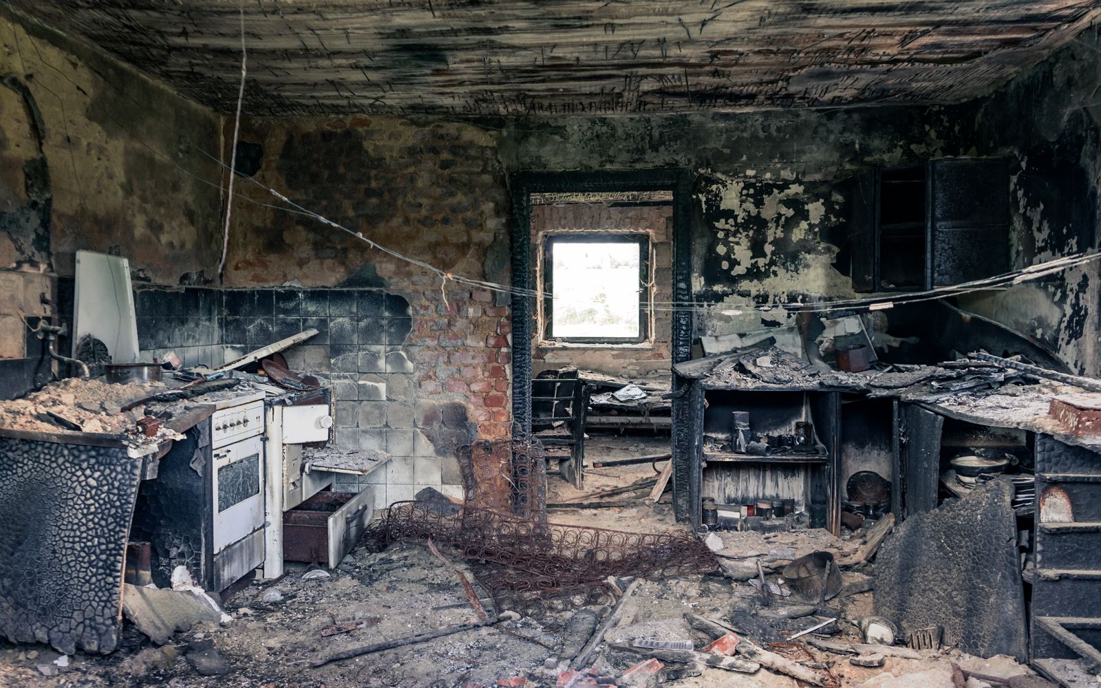 The charred interior of a house damaged by fire, with blackened walls and surfaces