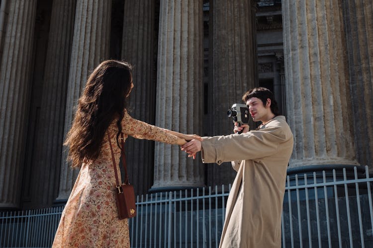 Man Filming A Woman While Holding Hands