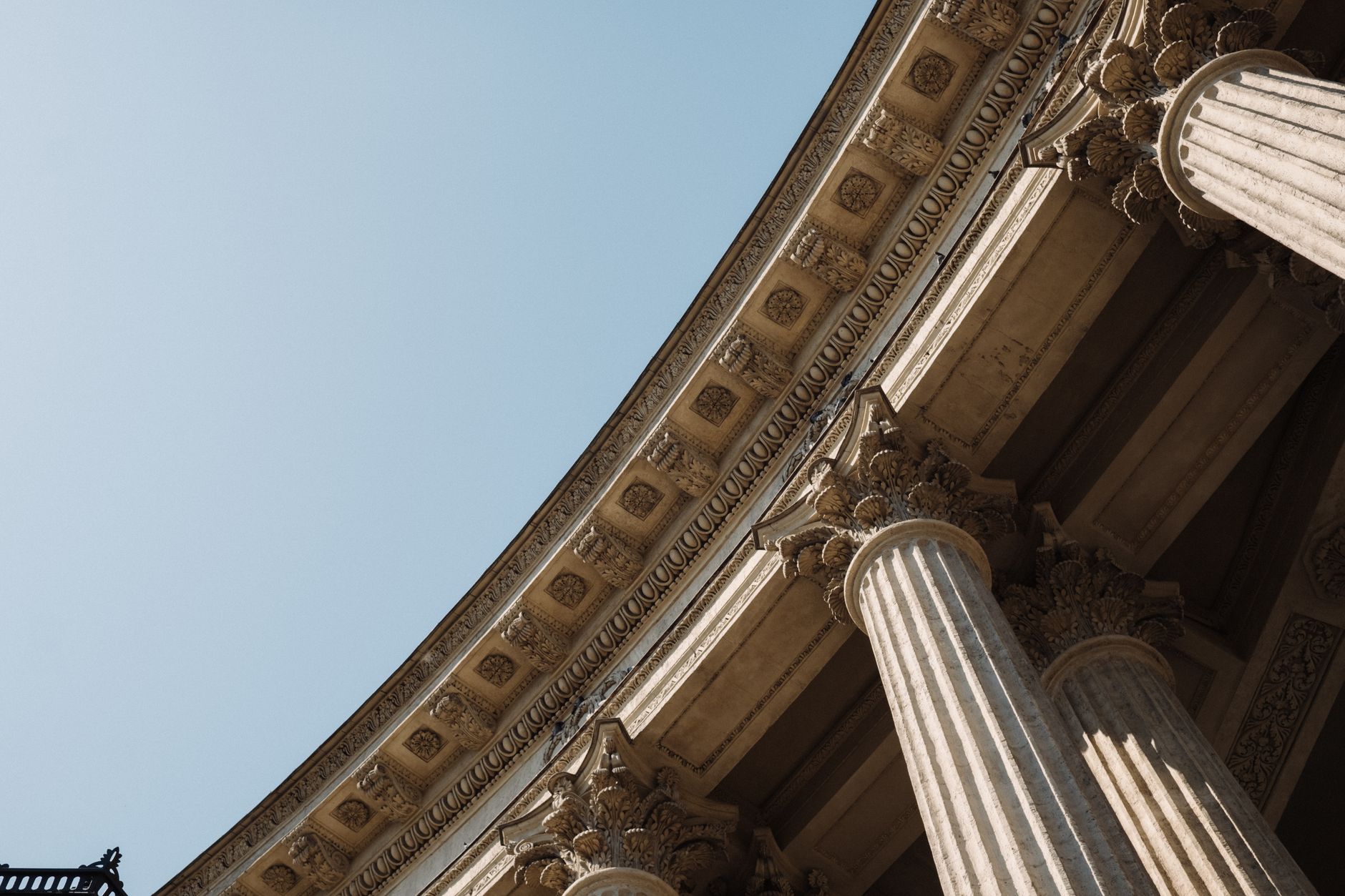 Detailed low-angle view of classical columns against a clear sky reflecting historical architectural grandeur.
