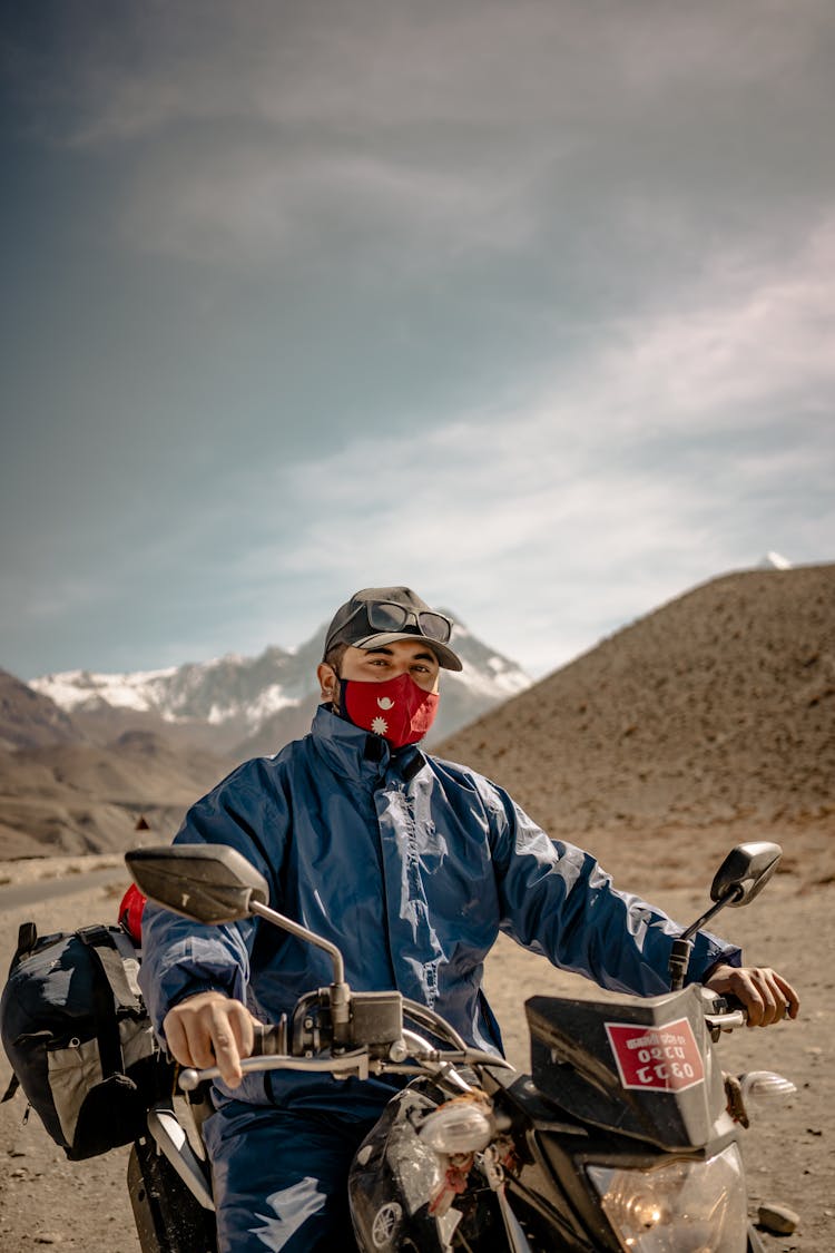 Portrait Of Man In Face Mask On Motorcycle In Desert