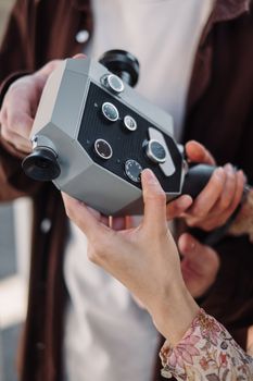A close-up view of hands holding a vintage analog camera, showcasing its intricate design.