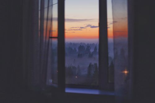 Free A peaceful view of a misty forest at sunset seen through a window, creating a tranquil atmosphere. Stock Photo