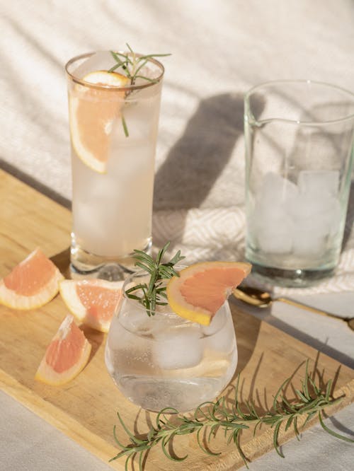 Free A Shot of Glasses Filled With Water, Ice Cubes, Grapefruit on Wooden Board  Stock Photo
