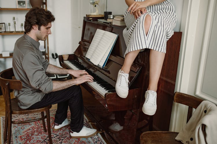 Woman Sitting On Piano And Man Playing