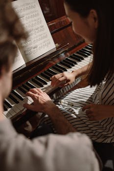 A couple enjoys playing piano together, hands on keys, creating music indoors.