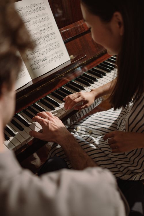 Free A couple enjoys playing piano together, hands on keys, creating music indoors. Stock Photo