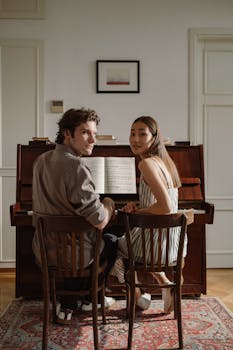 A couple sitting together playing piano in a cozy living room setting.