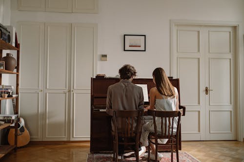 Free Back View of a Couple Playing the Piano Together Stock Photo