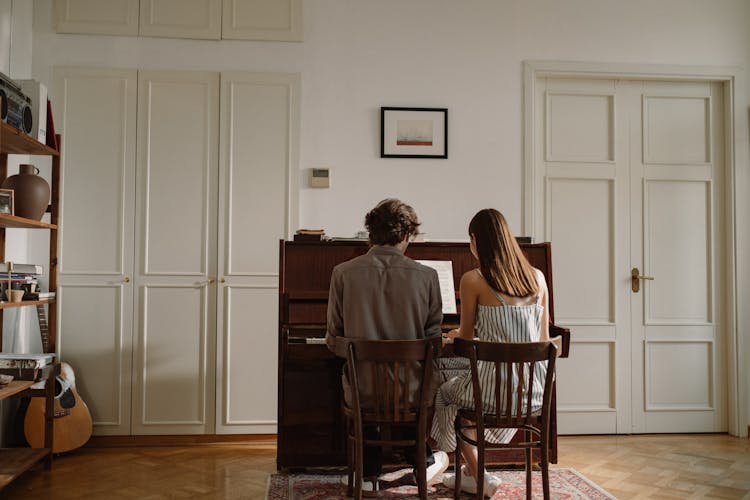 Back View Of A Couple Playing The Piano Together