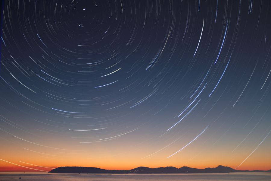 Star trails over the ocean horizon at twilight