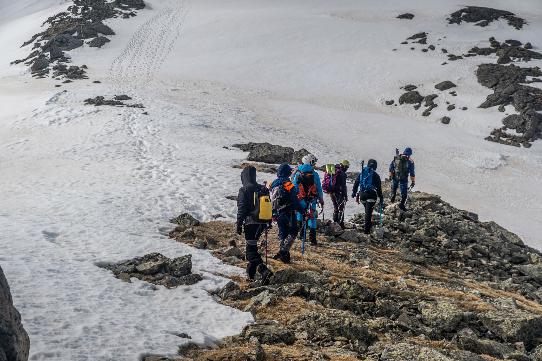 Adventurous group hiking on a snowy mountain ridge during winter, showcasing teamwork.