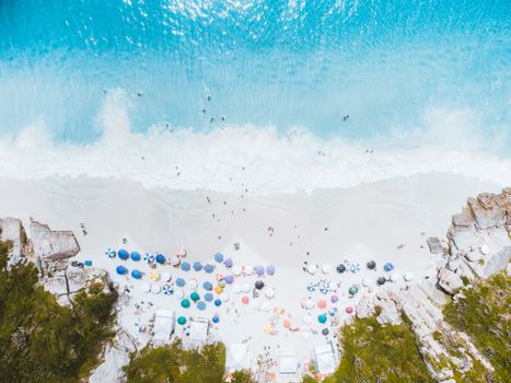 A breathtaking aerial view of Prainhas do Pontal beach in Arraial do Cabo, Brazil, showcasing vibrant umbrellas and crystal clear waters.