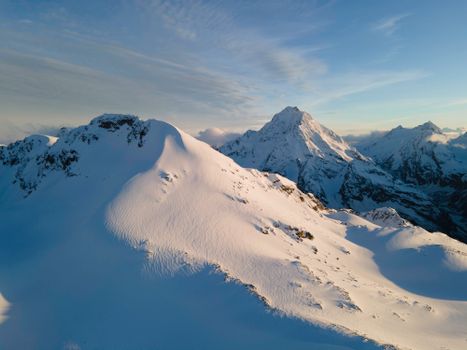 Discover the serene beauty of snowy mountain peaks under a clear winter sky.