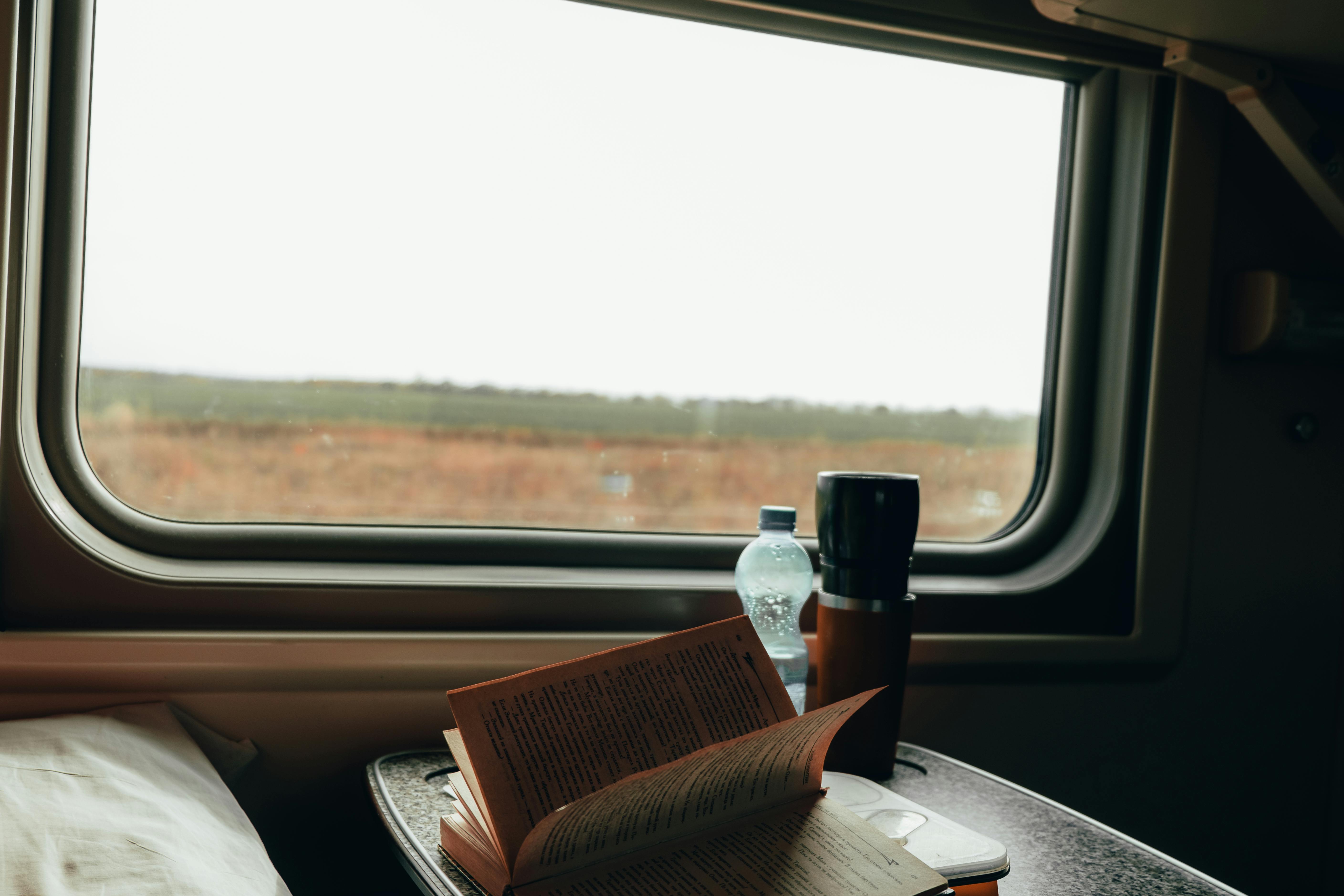 A cozy train journey scene featuring an open book and scenic window view, ideal for travel inspiration.