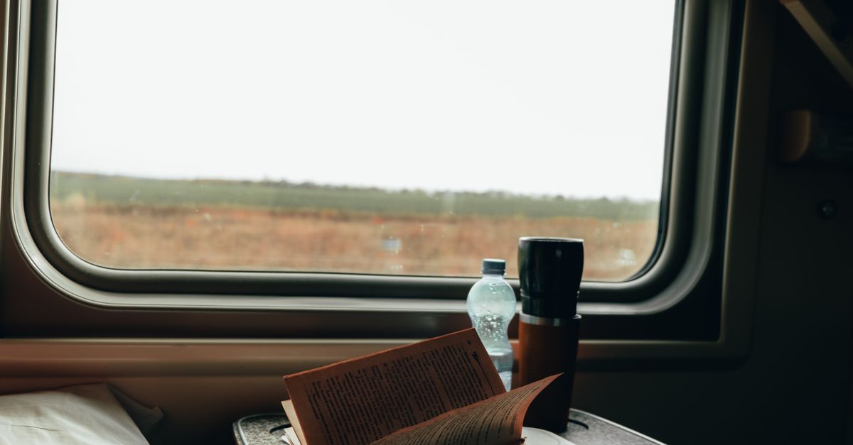 A minimalist travel kit with a small backpack, reusable water bottle, and a book