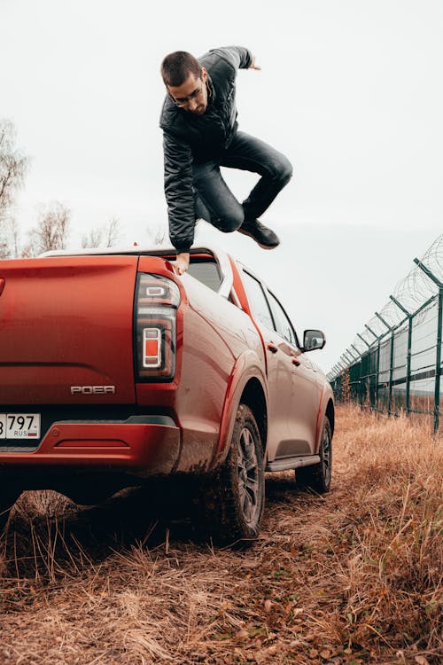 Man Jumping Out of a Red Car