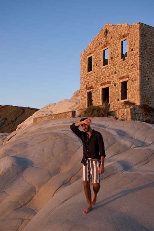 Free Man walking near an old stone building at sunset in a deserted area. Stock Photo