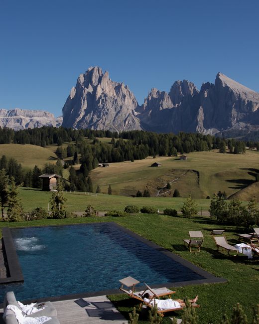 Serene landscape featuring a pool with a breathtaking view of alpine mountains.