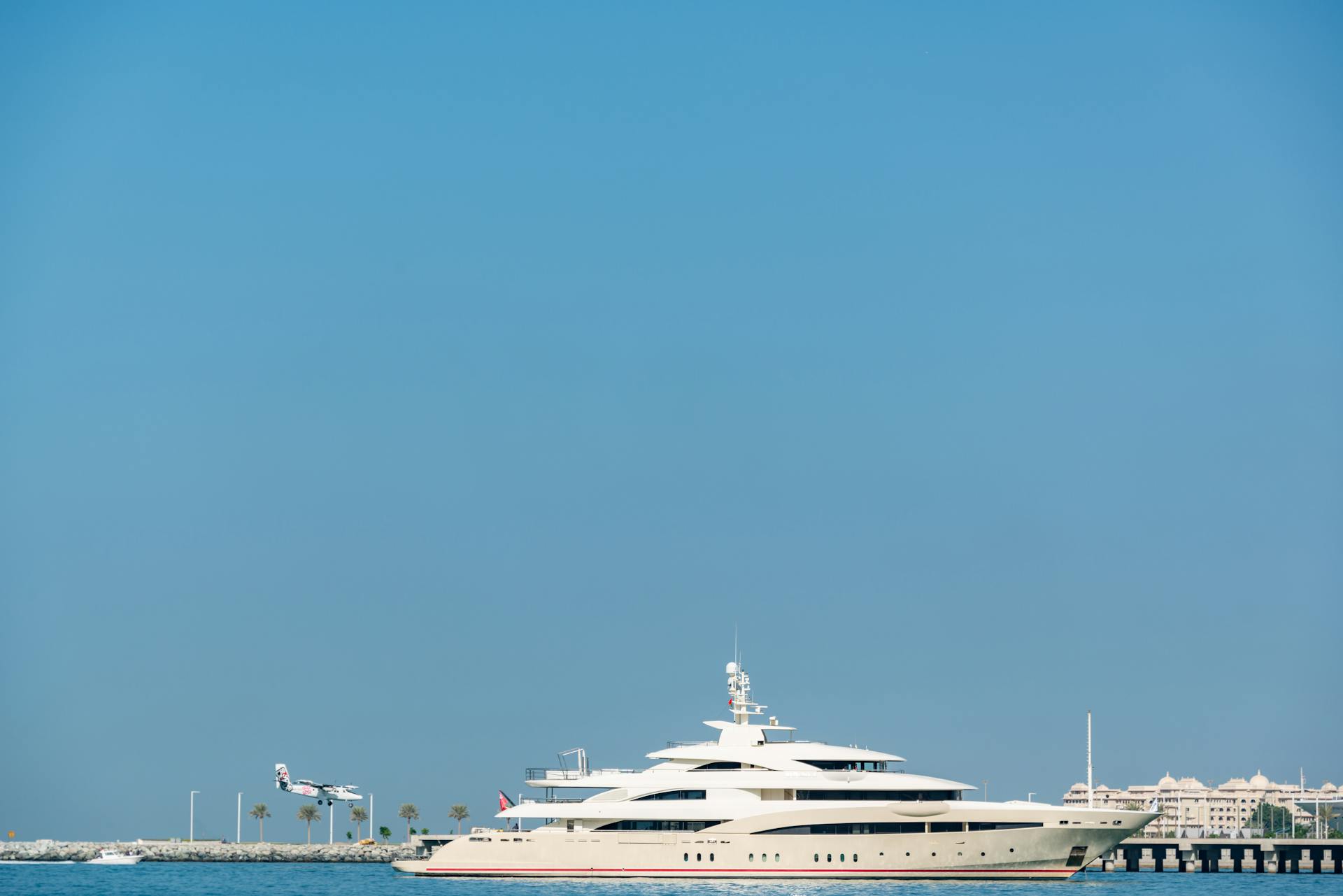 Elegant luxury yacht sailing on open sea with clear blue sky backdrop, conveying leisure and opulence.