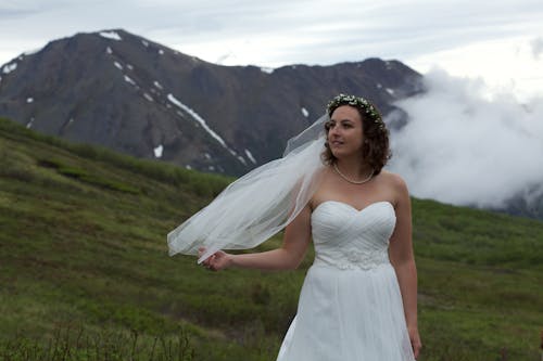 無料 白いウェディングドレスを着て草の上に立っている女性 写真素材