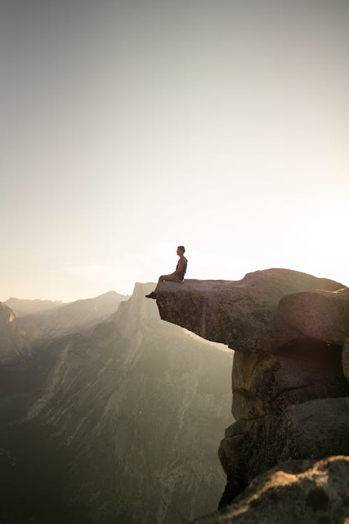 Free Photo of a Man Sitting on the Edge of a Cliff Stock Photo
