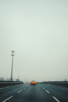A lone taxi drives down a foggy highway, creating a sense of solitude and mystery.