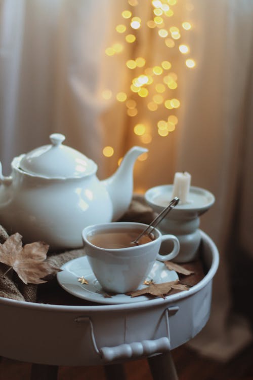 A High Angle View of a Tea in a Cup Next to a Porcelain Teapot