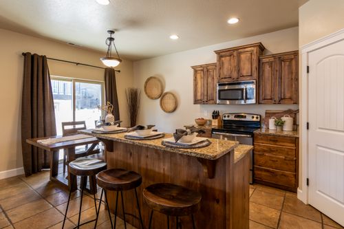 Free A cozy, modern rustic kitchen featuring wooden cabinets and a central island with seating, designed for comfort and style. Stock Photo