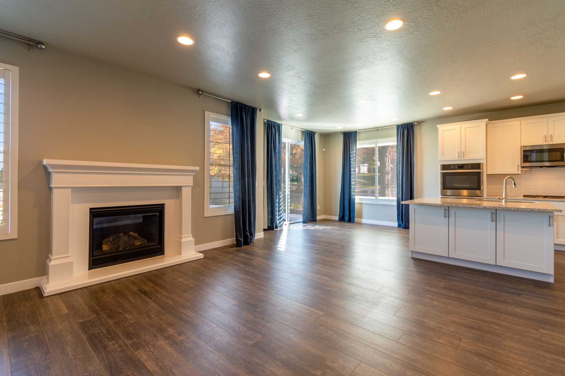 Elegant open layout with modern kitchen, cozy fireplace, and wooden flooring.