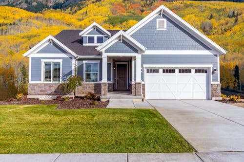 Free Facade of a Suburban Family House in a Valley with Autumnal Trees in the Background  Stock Photo