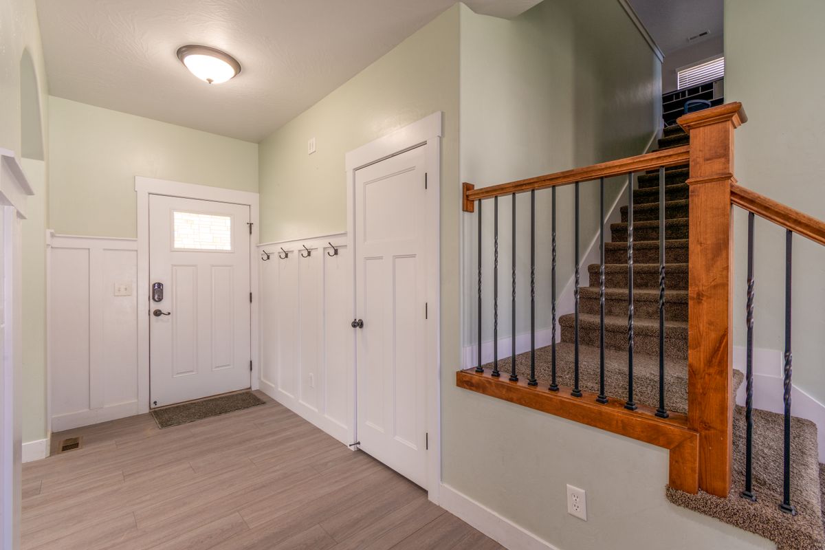 Entryway with wall mounted coat hooks and white door