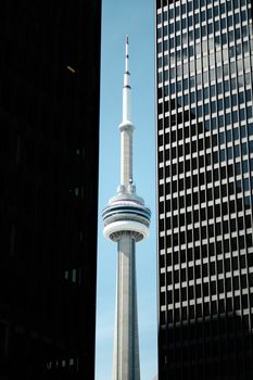CN Tower seen between skyscrapers in Toronto's downtown financial district, iconic landmark view.