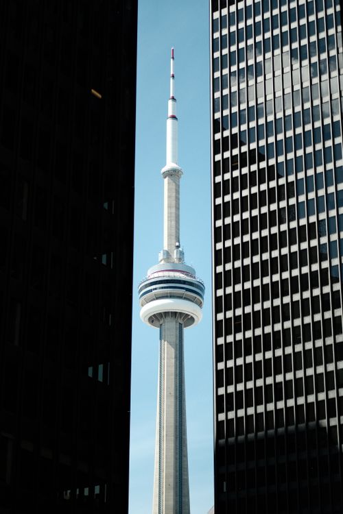Free CN Tower seen between skyscrapers in Toronto's downtown financial district, iconic landmark view. Stock Photo