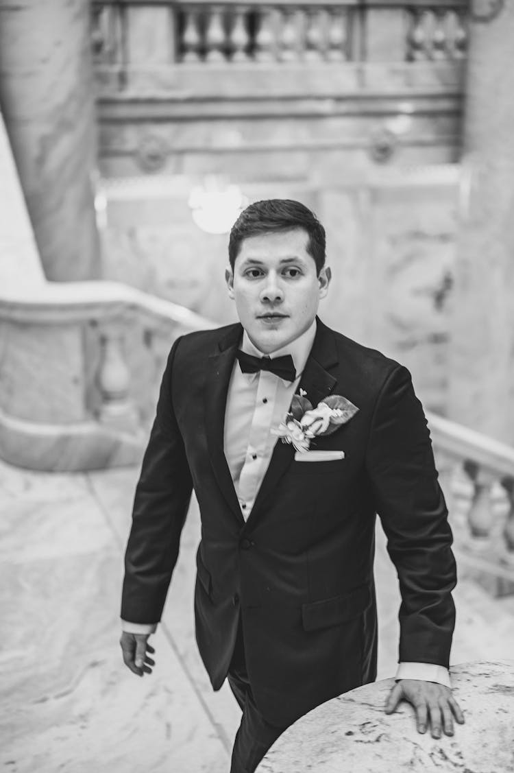 Groom In Black Suit Walking Up Marble Stairs