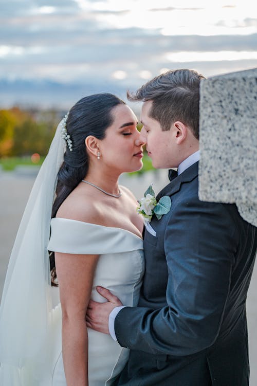 Man in Black Suit Kissing Woman in White Wedding Dress