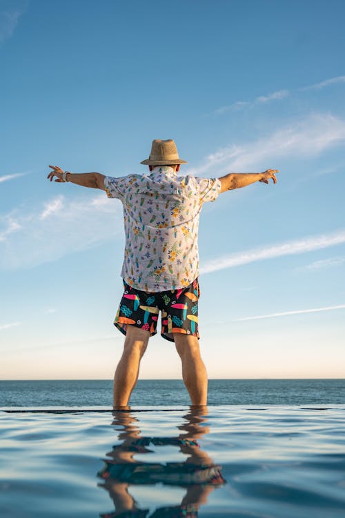 Man in White and Black Checkered Shirt and Green Shorts Standing on Beach