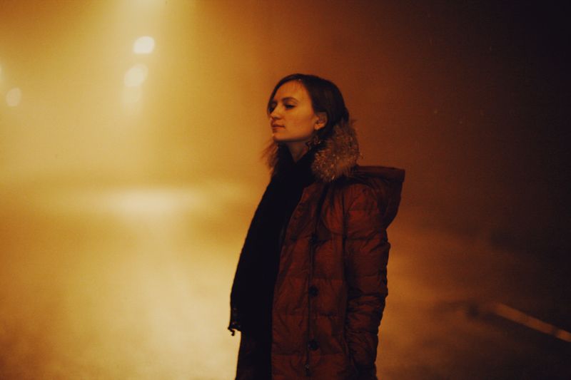 Woman in a winter jacket on a foggy street at night