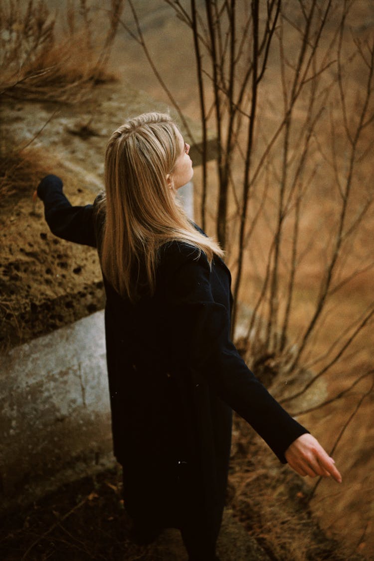 Woman Standing On Stairs Of Abandoned Building With Arms Stretched Out