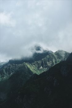 Fog-covered green mountains with a dramatic sky create a mysterious and serene atmosphere.