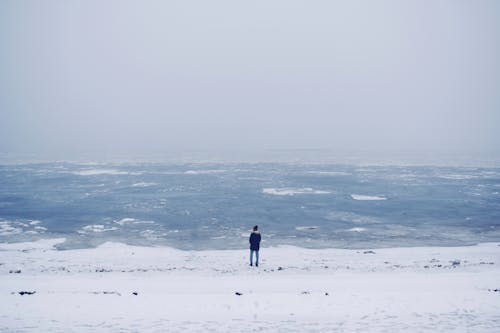 A Person Standing in the Snow Covered Beach
