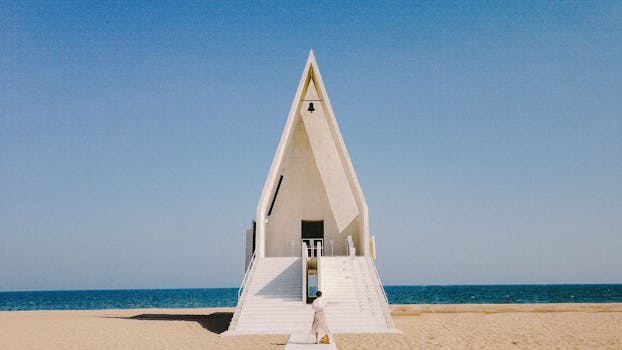 A contemporary chapel on a sandy beach in Qinhuangdao, China, with clear blue skies and ocean horizon.