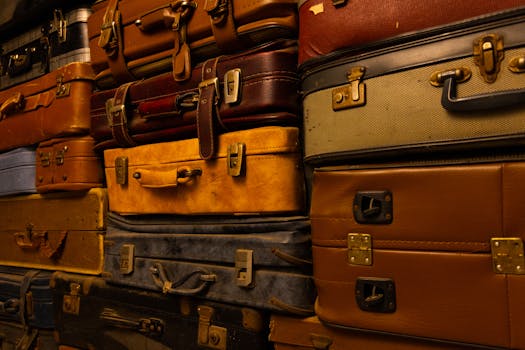 Stack of vintage suitcases showcasing assorted colors and textures in warm lighting.