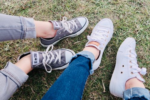 Free Casual footwear featuring Converse sneakers on a grassy outdoor setting, ideal for fashion and lifestyle themes. Stock Photo