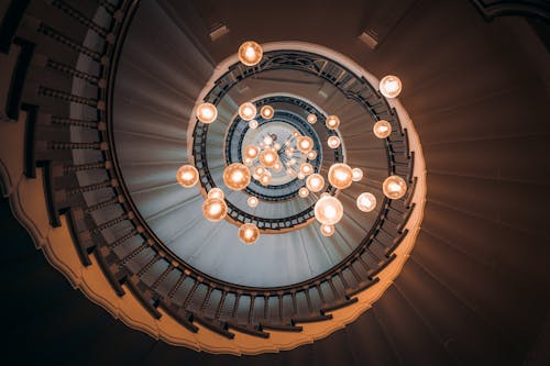 Free Elegant spiral staircase in London with a stunning chandelier, creating a mesmerizing visual effect. Stock Photo
