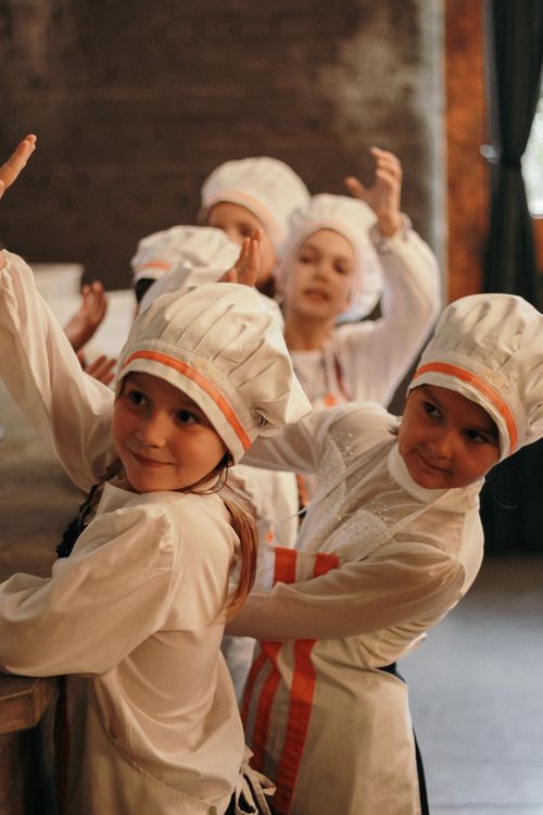 Free Group of children in chef uniforms engaging in a fun cooking class indoors. Stock Photo